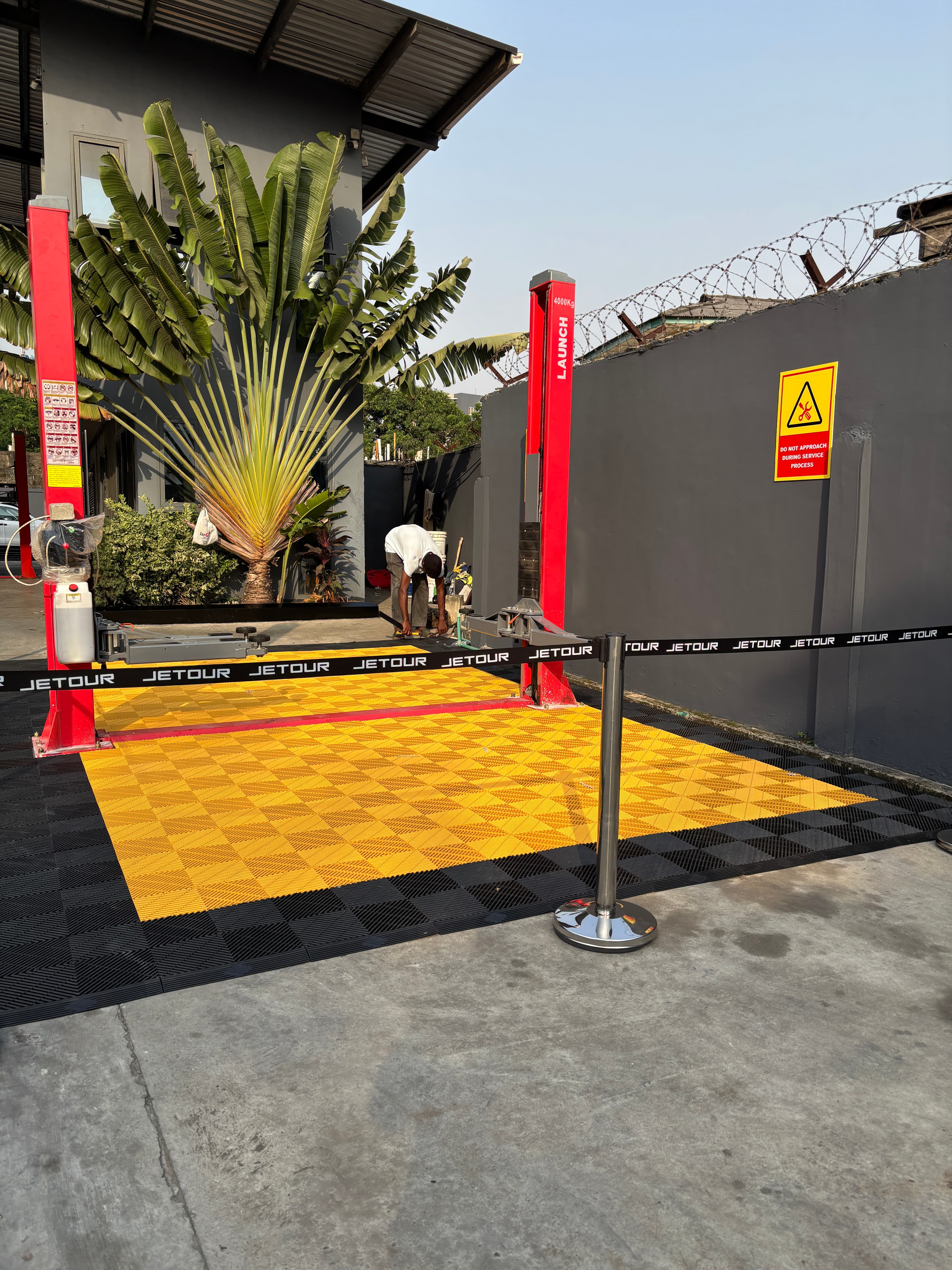 JETOUR launch event — yellow & black checker floor with vehicle lifts