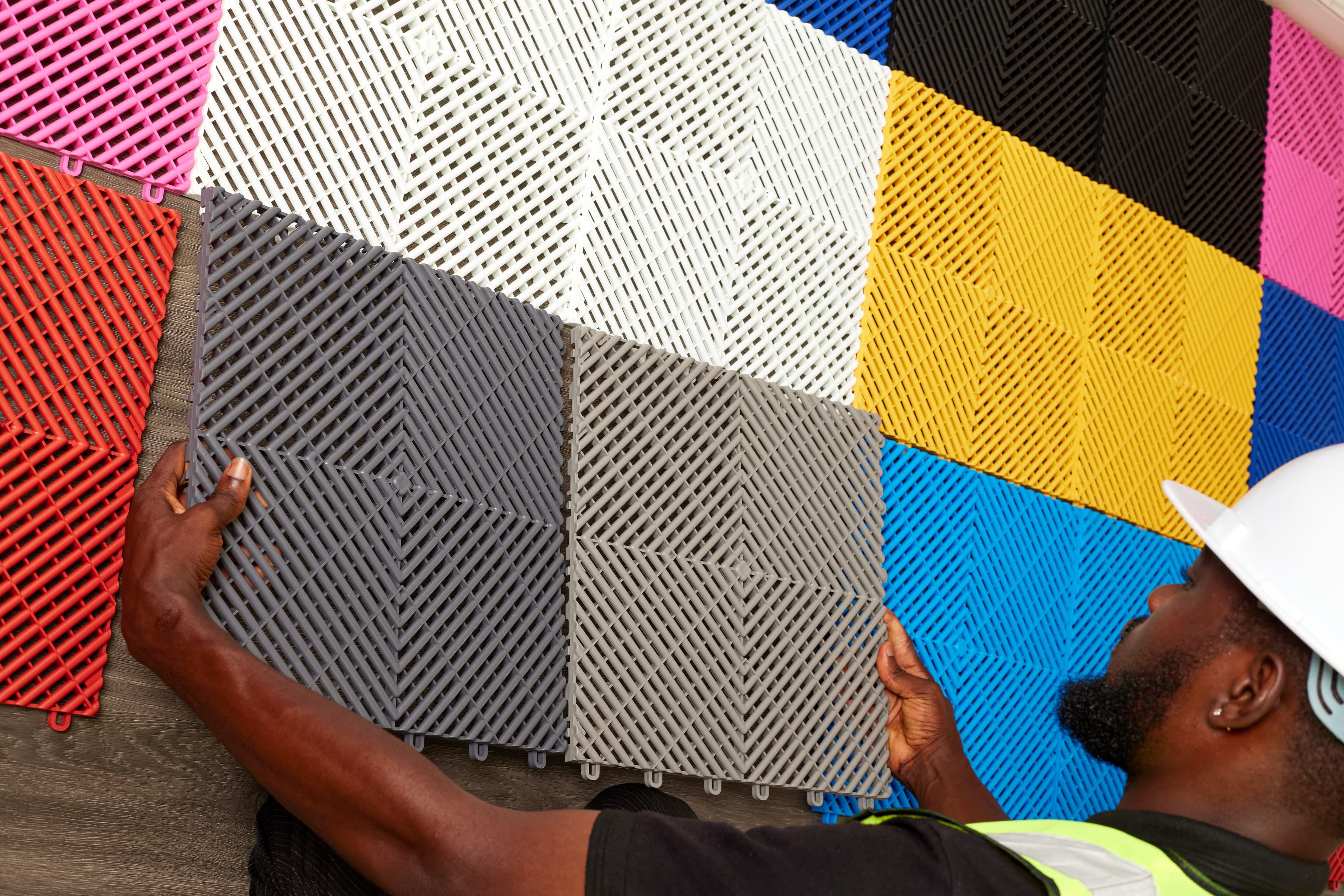 Installer placing grey interlocking tile arrangement
